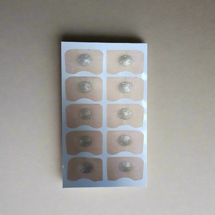 Sheet of adhesive patches with silver dots on a wooden surface